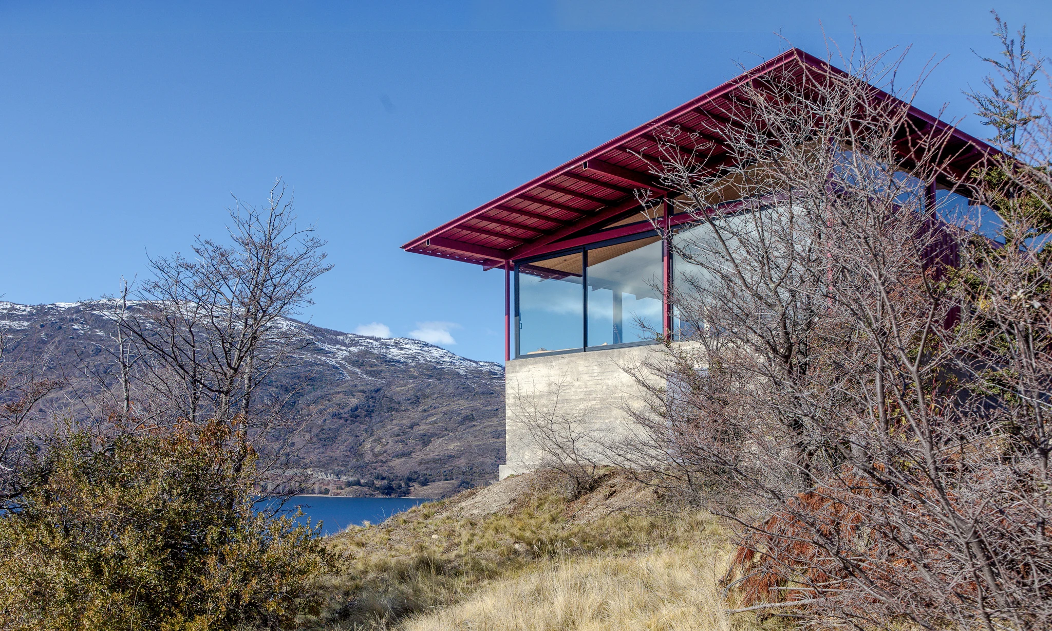 Casa Ñire: cubierta roja, estructura esbelta y podio de hormigón sobre la ladera